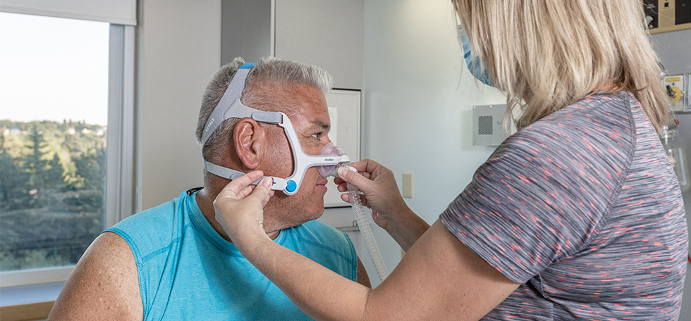 Sleep specialist helping man fit a cpap mask