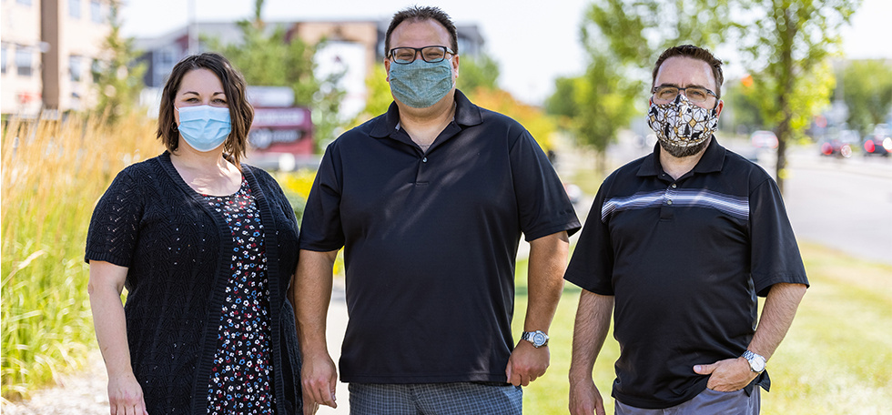 two men and women standing wearing masks